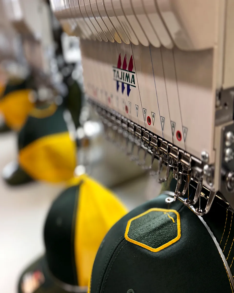 A Tajima embroidery machine stitching a logo at QHL in Quincy